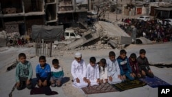 Warga Palestina salat di depan masjid yang hancur akibat serangan udara Israel di Rafah, Jalur Gaza, Jumat, 8 Maret 2024, menjelang bulan suci Ramadan. (Foto: AP/Fatima Shbair)