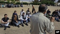 New recruits listen as a training instructor schools them in disassembling, cleaning, and use of AK47 automatic weapons, at a rebel forces training camp in Benghazi, Libya, April 5, 2011