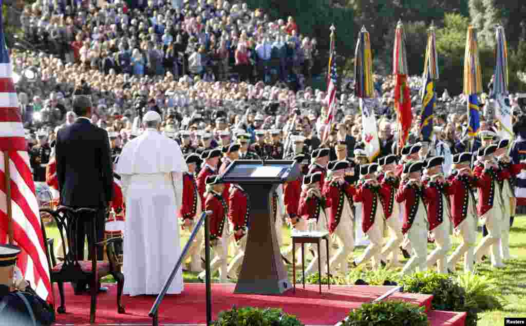 U.S. President Barack Obama and Pope Francis watch onstage as the "Old Guard" fife and drum corps marches past during an official welcome ceremony on the South Lawn of the White House, Sept. 23, 2015.