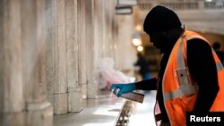 FILE - A Metropolitan Transportation Authority (MTA) staff member uses Lysol to clean a station at the lobby of Grand Central Station following the outbreak of coronavirus disease (COVID-19), in New York City, March 16, 2020. 