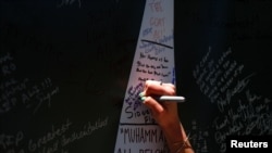 Một người hâm mộ viết lên tấm bảng dòng chữ "I AM ALI" trong khi bày tỏ lòng kính trọng đối với nhà vô địch quyền Anh Muhammad Ali tại Trung tâm Nghệ thuật Trình diễn Kentucky, ngày 8 tháng 6 năm 2016.