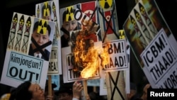 FILE - A man burns banners being held by protesters during an anti-North Korea rally in central Seoul, South Korea, Feb. 11, 2016.