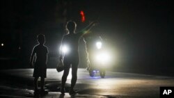 Una mujer y un niño a la espera de conseguir un transporte durante el apagón programado de electricidad en Bauta, Cuba, el lunes 18 de marzo de 2024. La isla enfrenta una crisis de energía, con varios apagones en las últimas semanas.