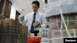 A bank employee stacks Vietnamese dong banknotes at the Vietcombank's headquarters in Hanoi on April 6, 2012. 