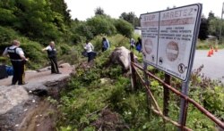 FILE - Royal Canadian Mounted Police officers greet migrants as they enter into Canada at an unofficial border crossing at the end of Roxham Road in Champlain, N.Y., Aug. 7, 2017.