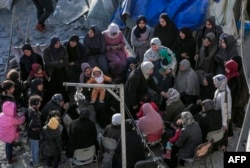 Palestinians sit amid tents and makeshift shelters that were destroyed in Israeli strikes in Deir el-Balah in central Gaza on March 2, 2024.