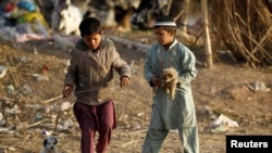 Children play with puppies at an Afghan refugee camp in Islamabad, Pakistan, Feb. 2, 2018.
