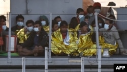 Migrants warmed by emergency blankets arrive on a boat of the Italian Guardia Di Finanza law enforcement agency on May 17, 2021 to disembark on the southern Italian Pelagie Island of Lampedusa. 