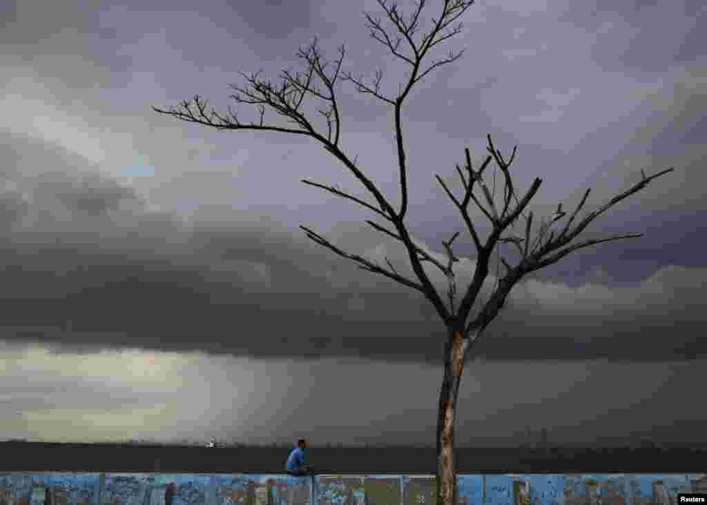 Seorang pria duduk di tembok penghalang air laut di Muara Karang, Jakarta.