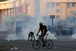 A demonstrator covers a tear gas canister in a bucket during a protest against Chile's state economic model in Santiago, Chile, Oct. 26, 2019.