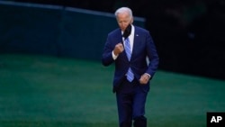 FILE - President Joe Biden takes off his mask as he walks from Marine One on the South Lawn of the White House in Washington, Oct. 5, 2021, after returning from a trip to Michigan to promote his infrastructure plan.