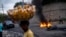 A street vendor walks past a barricade of burning tires during a demonstration against high prices and fuel shortages in Port-au-Prince, on Oct. 21, 2021. 