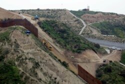 In this March 11, 2019 photo, construction crews replace a section of the primary wall separating San Diego, above right, and Tijuana, Mexico, below left, seen from Tijuana, Mexico.