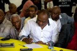 Senator Youri Latortue signs an agreement with leaders from the opposition, to choose an interim president in place of President Jovenel Moise.