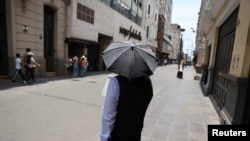 Un hombre camina por las calles del centro de la ciudad con un paraguas debido a las altas temperaturas en Lima, Perú, el 25 de febrero de 2024.