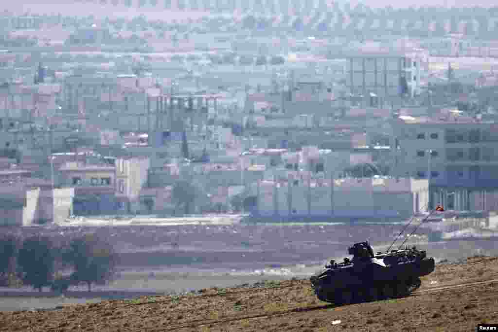 A Turkish army tank drives in front of the ruins of Kobani (seen in the background) near the Turkish-Syrian border, Oct. 24, 2014. 