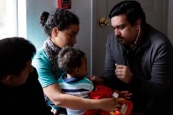 Dr. Martin Garza, right, a pediatrician who volunteers at Catholic Charities in McAllen, Texas, checks migrant families just released from immigration detention, March 15, 2019.