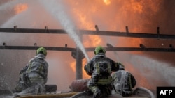 This handout photograph taken on June 12, 2024 and released on June 13, 2024 by the Ukrainian Emergency Service, shows firefighters trying to stop a fire at an industrial facility damaged following an air strike, in the Kyiv region, amid the Russian invas