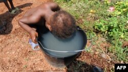 FILE - A child drinks from a bucket in the catholic youth center Don Bosco in Bangui where thousands of internally displaced people, including hundreds of children, live, according to calculations undertaken by UNICEF.