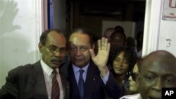 Haiti's former dictator Jean-Claude "Baby-Doc" Duvalier, center, waves to the media upon his arrival at the Toussaint Louverture international airport in Port-au-Prince, Haiti, 16 Jan. 2011.