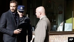 Italian journalists Gianluigi Nuzzi (R), and Emiliano Fittipaldi (L) talk with a Vatican Gendarmie guard at the Vatican City's Perugino entrance Nov. 24, 2015. 