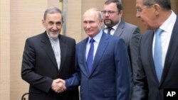 Russian President Vladimir Putin, center, shakes hands with Ali Akbar Velayati, a senior adviser to Iran's Supreme Leader Ayatollah Ali Khamenei, as Russian Foreign Minister Sergey Lavrov, stands at right, at Novo-Ograyovo outside in Moscow, Russia, July 12, 2018. 