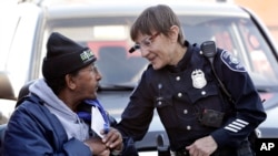FILE - Seattle Police Officer Debra Pelich, right, wears a video camera on her eyeglasses as she talks with Alex Legesse before a community gathering in Seattle. While the Seattle Police Department bars officers from using real-time facial recognition in body camera video, privacy activists are concerned that a proliferation of the technology could turn the cameras into tools of mass surveillance. The ACLU and other organizations on May 22, 2018, asked Amazon to stop selling its facial-recognition tool, called Rekognition, to law enforcement agencies.