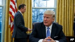 Presiden AS Donald Trump duduk di meja kantornya di Gedung Putih (23/1). (AP/Evan Vucci)