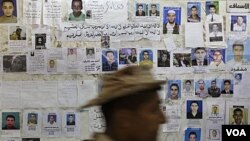 Seorang melewati sebuah poster yang menunjukkan foto-foto "warga Libya yang hilang" di sebuah rumah sakit di Benghazi (17/4).