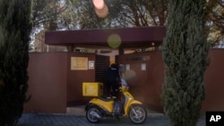 FILE - A Spanish postman talks to a member of North Korea's embassy, not seen, in Madrid, March 13, 2019. 