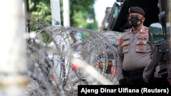 Seorang petugas polisi berjaga di luar gedung Pengadilan Negeri Jakarta Timur saat persidangan ulama Rizieq Shihab digelar di Jakarta, pada 27 Mei 2021. Beberapa pekan terakhir, banyak kasus bermunculan yang menodai citra polisi Indonesia. (Foto: Reuters/Ajeng Dinar Ulfiana)