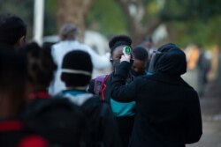 The temperature of a grade 7 pupil is taken as she returns to the Meldene Primary School in Johannesburg Monday, June 8, 2020.