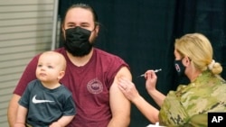 Isaac Hoffman holds his son Leo, 10 months, while receiving his Pfizer vaccine, March 25, 2021, in Spanish Fork, Utah. 