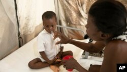 A mother hydrates her son who is stricken with cholera, at a clinic run by Doctors Without Borders in Port-au-Prince, Haiti, Friday, Nov. 11, 2022.