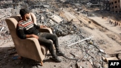 Човек седи на стол за одмор на високо оштетената зграда долж улицата Сафтави во Џабалија во северниот дел на Појасот Газа на 20 јануари 2025 година, еден ден откако стапи на сила договорот за прекин на огнот во војната меѓу Израел и Хамас.