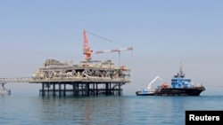 FILE - A ship is docked at a Al-Basra oil platform in the Middle East Gulf, Sept. 21, 2014. 