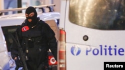 FILE - A Belgian special forces police officer patrols a street during a police raid in central Brussels, Belgium, Dec. 20, 2015. The ninth suspect arrested is believed to have been in contact via telephone with the cousin of the alleged organizer of the attacks.