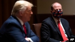 Colorado Gov. Jared Polis listens as President Donald Trump speaks during a meeting on the coronavirus response in the Cabinet Room of the White House, May 13, 2020, in Washington. 