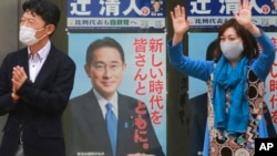 A supporter of Japan's governing Liberal Democratic Party waves by posters of Japanese Prime Minister Fumio Kishida during a campaign rally for the Oct. 31 lower house elections, in Tokyo, Oct. 27, 2021.
