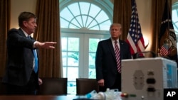 Associate director of the NASA jet propulsion laboratory Dave Gallagher shows President Donald Trump a ventilator created by their engineers during a demonstration in the Cabinet Room of the White House, April 24, 2020, in Washington. 