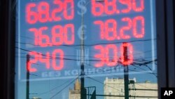 FILE - The building of the Russian Foreign Ministry, center back, is reflected in a sign showing currency exchange rates in Moscow, Russia, Aug. 21, 2015. The U.S. Senate on Wednesday moved to strengthen sanctions against Russia for its meddling in the 2016 presidential election.
