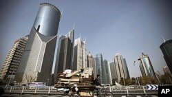 A junk collector rides his tricycle with high-rising buildings as background in Shanghai, China, Dec. 7, 2010