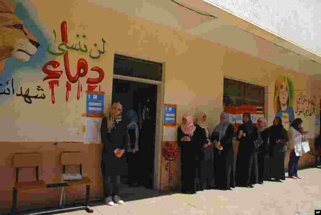 Libyan voters line up at a polling station in Benghazi, July 7, 2012. Jubilant Libyans marked a major step toward democracy after decades of rule by&nbsp;dictator Moammar Gadhafi. &quot;Don&#39;t forget the blood of the martyrs&quot; is in Arabic at left.