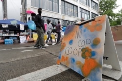 People walk near what is being called the "No Cop Co-op" were protesters and others can get free food and other supplies, June 11, 2020, inside what is being called the "Capitol Hill Autonomous Zone" in Seattle.