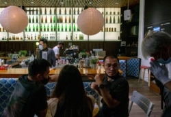 A steward greets a group of customers at a pub in Bangkok, Thailand, July 1, 2020.