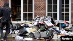 A member of a television crew is seen beside burnt files and documents in front of a building of German newspaper Hamburger Morgenpost in Hamburg, Germany, Jan. 11, 2015.