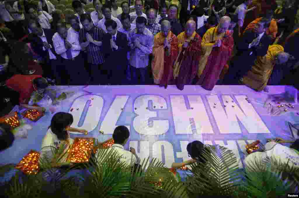 People place candles on a banner reading, "Pray for MH370" after a special prayer for passengers onboard the missing plane at the Malaysian Chinese Association headquarters in Kuala Lumpur, April 6, 2014. 