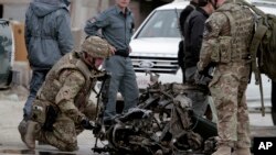 U.S. forces examine the remains of a car after a suicide car bomb attack on the Jalalabad-Kabul road in Kabul, Afghanistan, Dec. 27, 2013. 