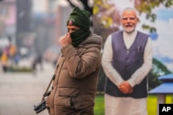Seorang polisi India berjaga di dekat potongan potret Perdana Menteri India Narendra Modi yang dipajang di pasar utama di Srinagar, Kashmir yang dikuasai India, Senin, 11 Desember 2023. (AP Photo/Mukhtar Khan)