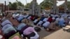 FILE - Indian Muslims offer Eid al-Fitr prayers in the shade of a petrol filling station as they join others offering prayers in an open area in Hyderabad, India, June 16, 2018. 